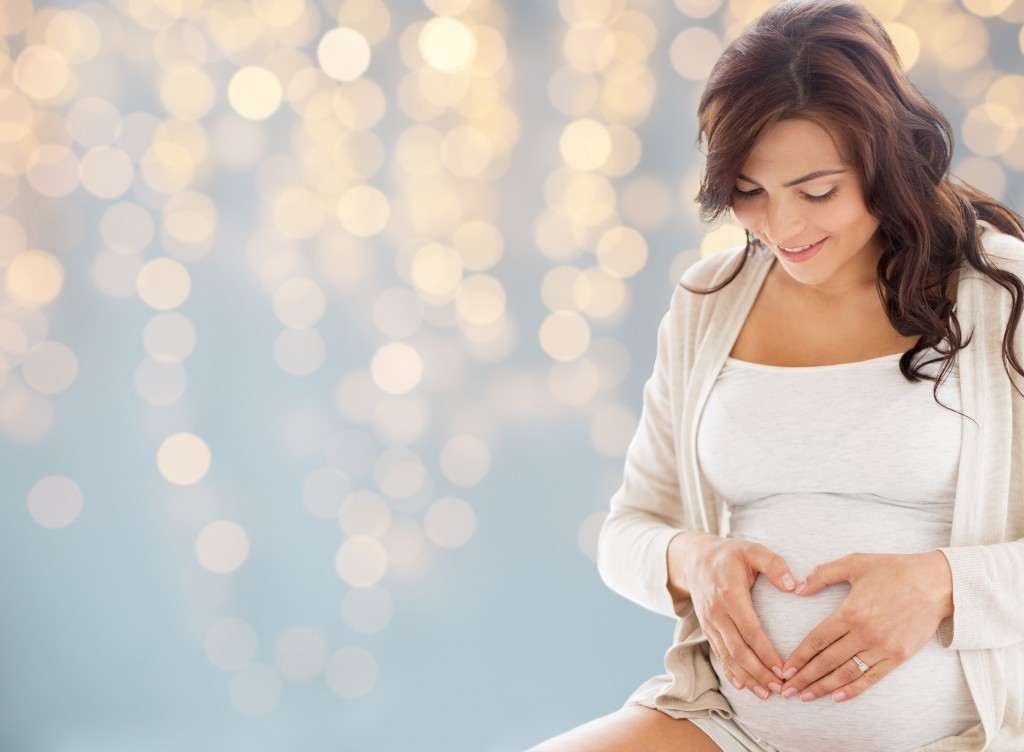 woman in maternity wearing a white clothing with lights as background